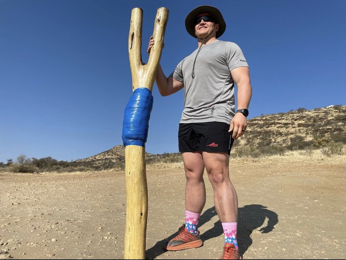 Francois outdoors beside a large wooden walking staff