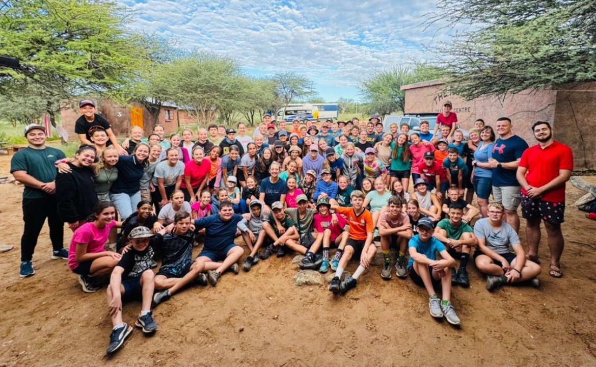 A large youth group gathered outdoors at camp